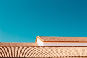 Rows of terracotta tiled roofs equipped with roof anchors, set against a clear blue sky in the background.