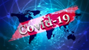 A world map with digital network lines features a bold red banner across it displaying the text "Covid-19" in large white letters.