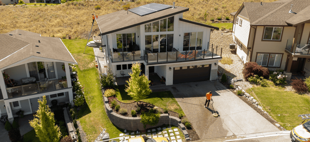 Technician pressure washing the driveway of a hillside Kelowna home