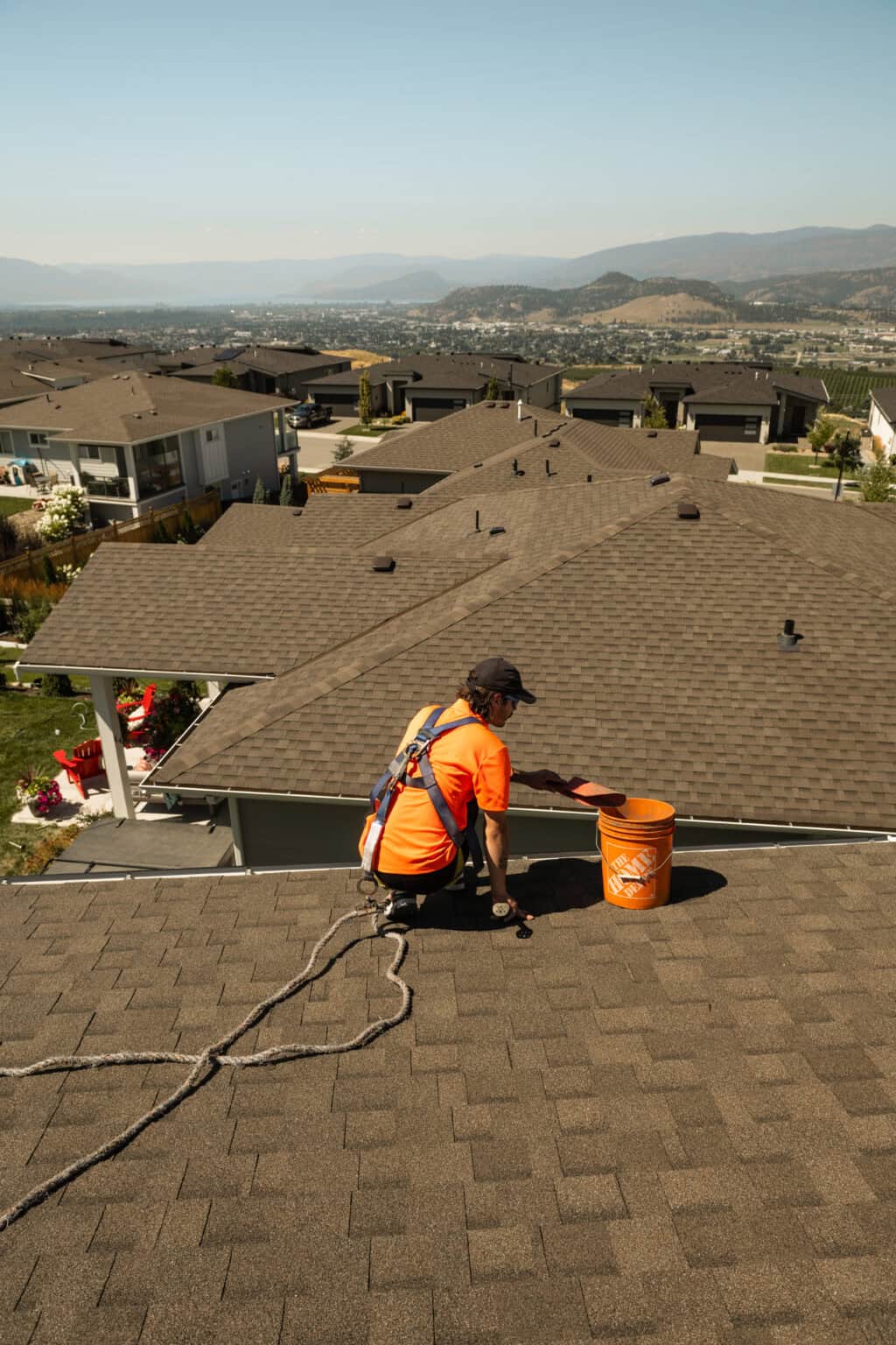Technician in a safety harness clearing gutter debris on a Kelowna-area rooftop