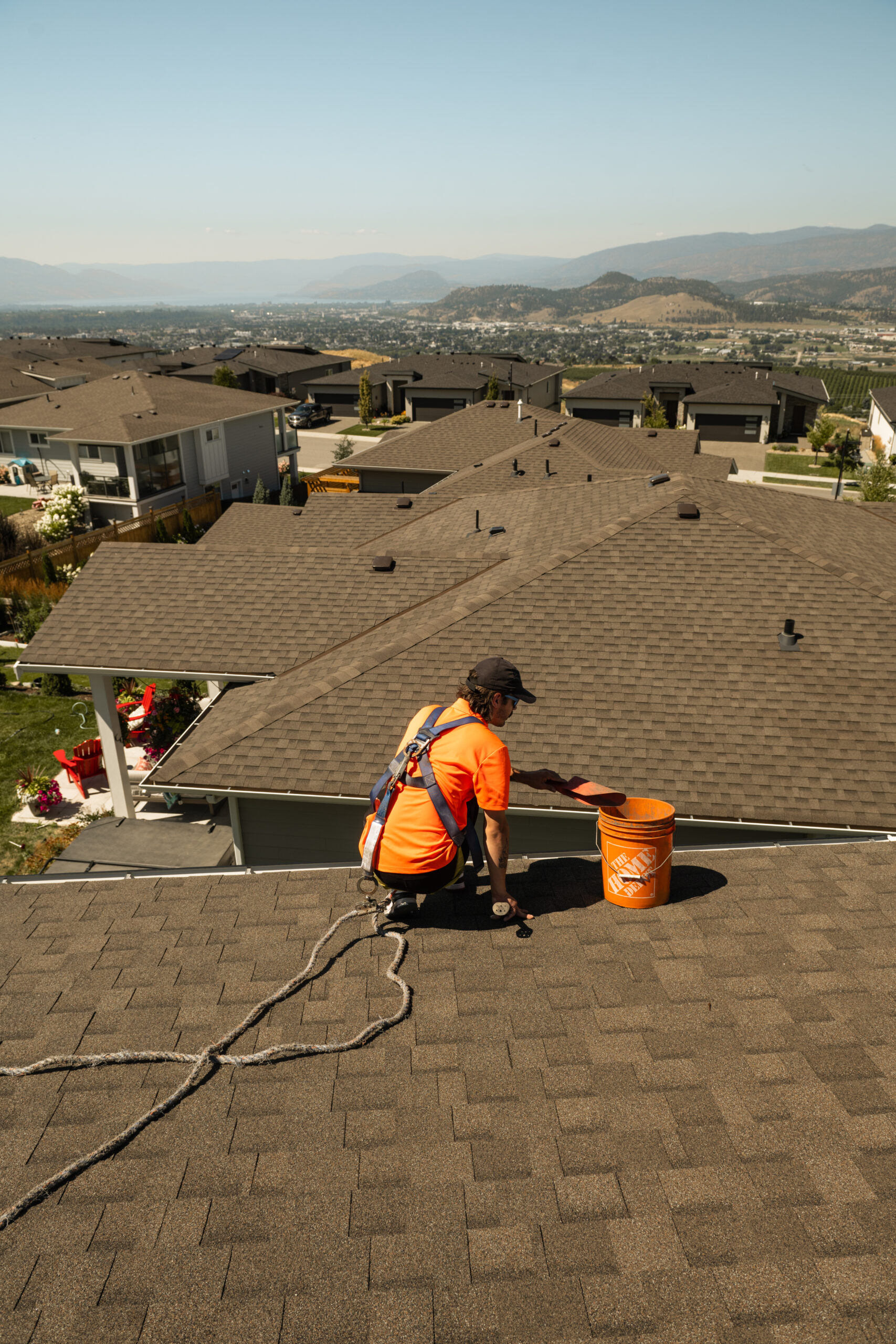 Live Next Level technician harnessed and clearing gutter debris on a Kelowna-area rooftop