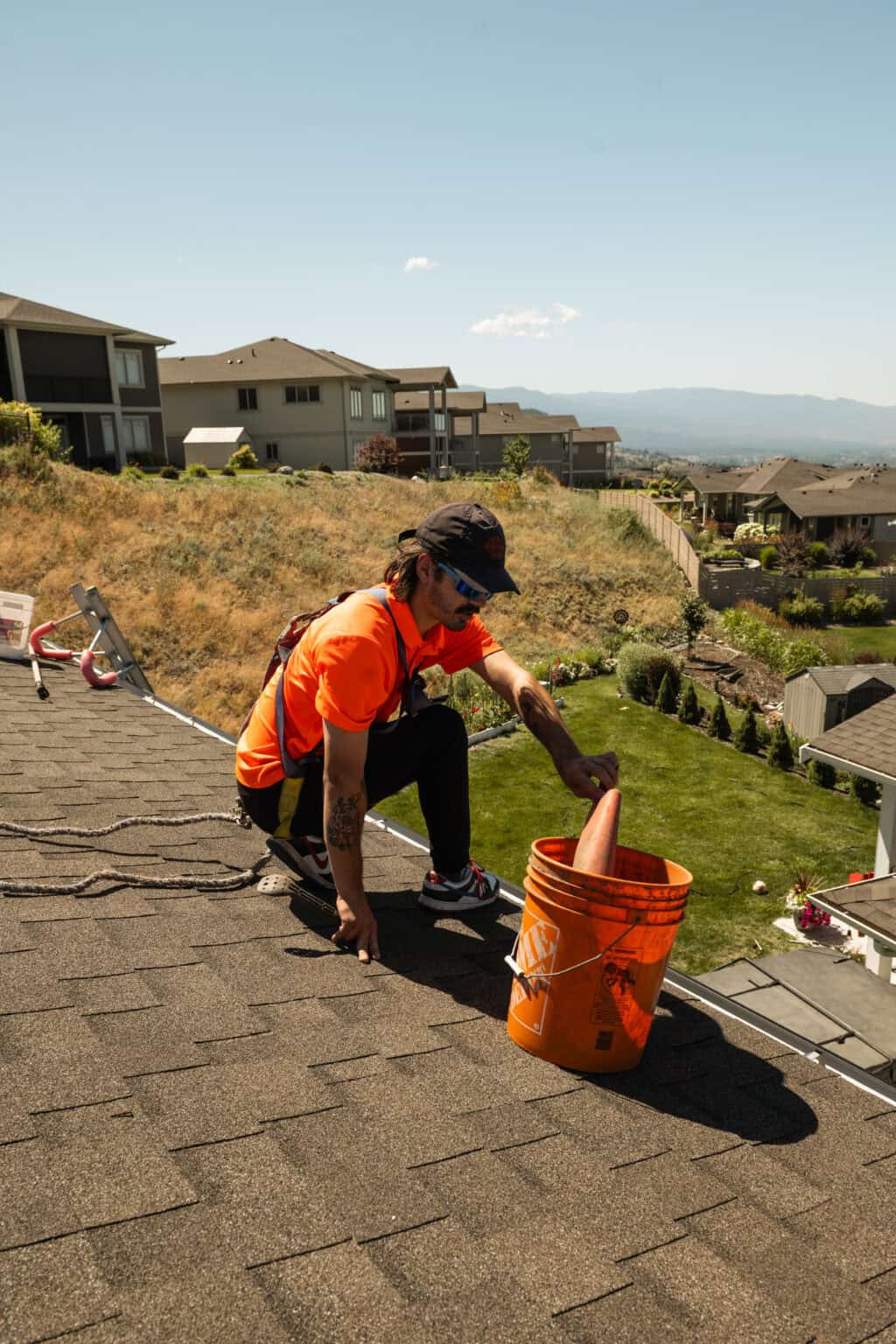 Technician scooping gutter debris into a bucket on the roof