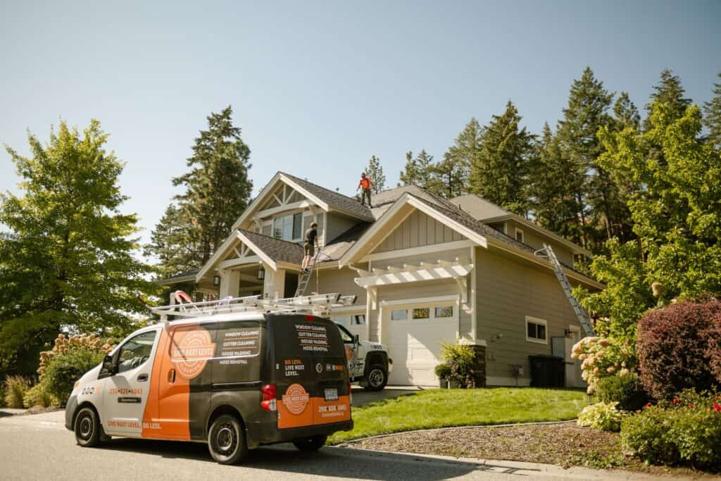 Live Next Level van parked outside a Kelowna home while a technician treats the roof for moss