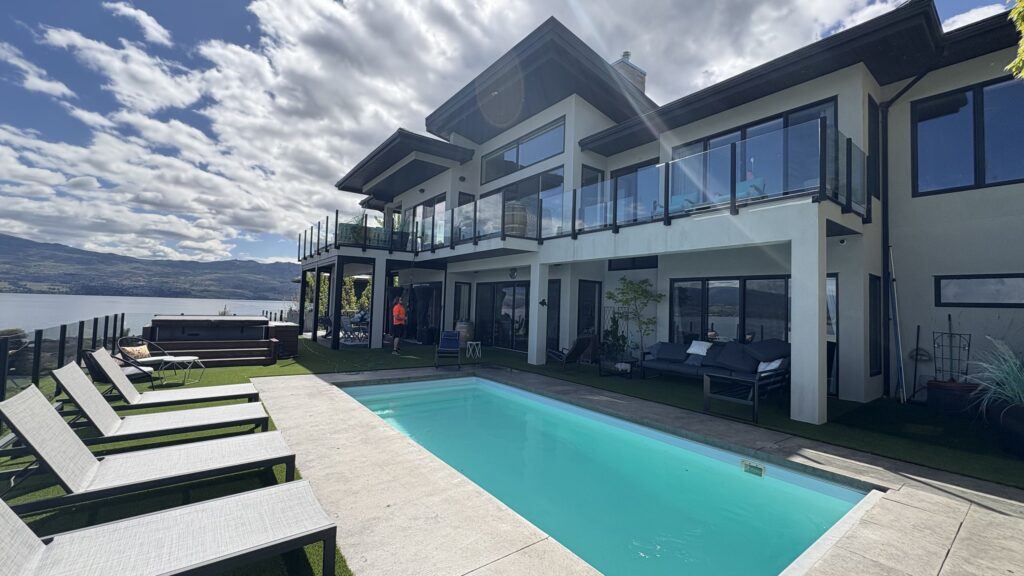 Live Next Level technician cleaning the windows of a lakeview Okanagan home with a pool