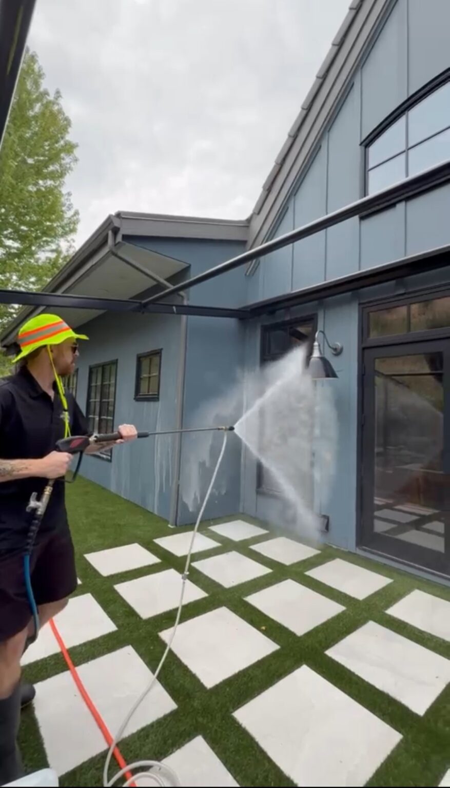 Technician soft washing fibre cement siding at low pressure on a Kelowna home